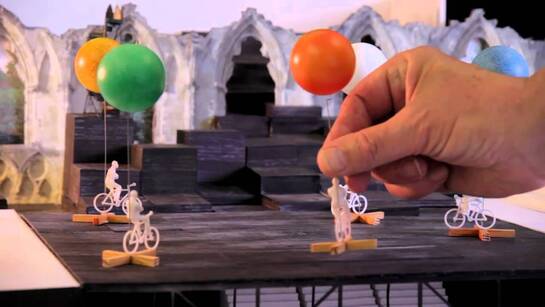 Models of bicycles with large balloons attached. A hand holds one.